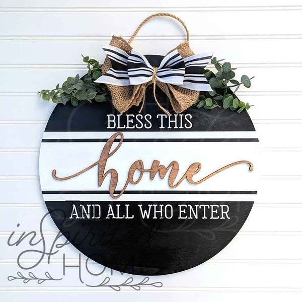 Decorative sign with 'Bless this home and all who enter' text, black and white striped bow, and greenery on a light blue background.